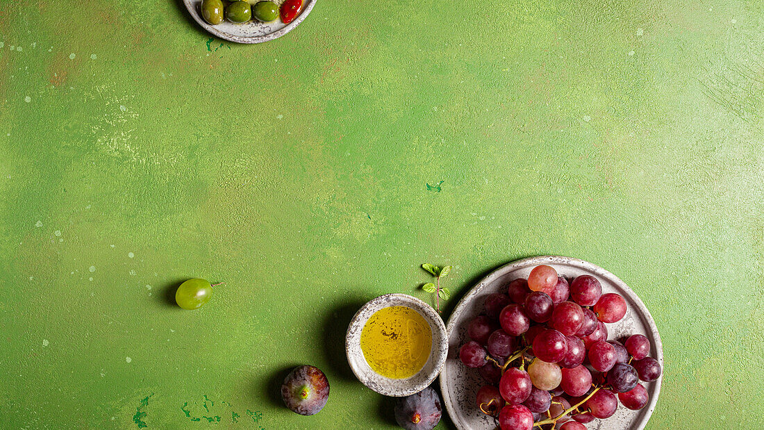 Draufsicht auf eine Traube köstlicher, frischer, saftiger, roter und grüner Weintrauben auf einem Teller mit grünem Hintergrund