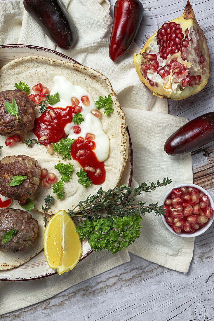 Traditional homemade beef and lamb meatballs with arabic bread, tomato sauce, pomegranate and aromatic herbs. Halal food