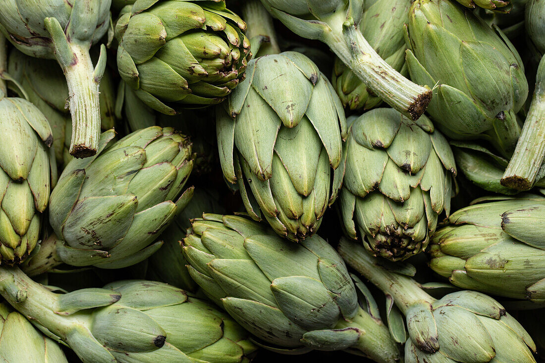 Top view full frame of bunch of fresh green artichokes placed on stall in local market