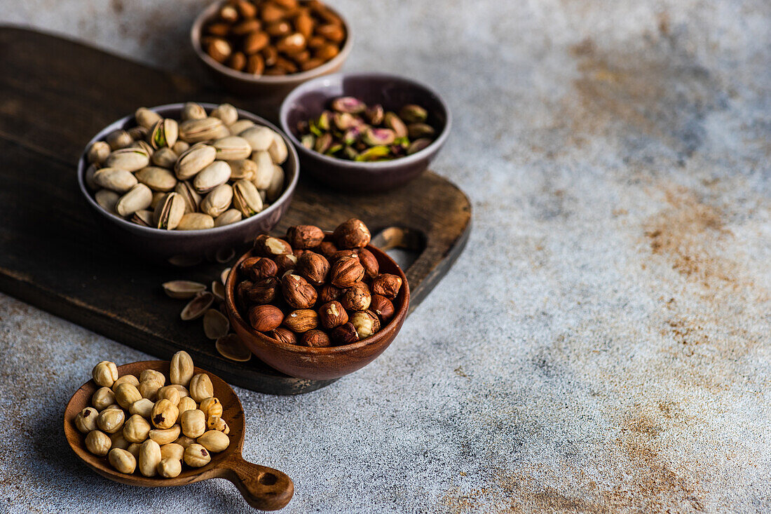 From above bowls with different kinds of nuts on concrete table background