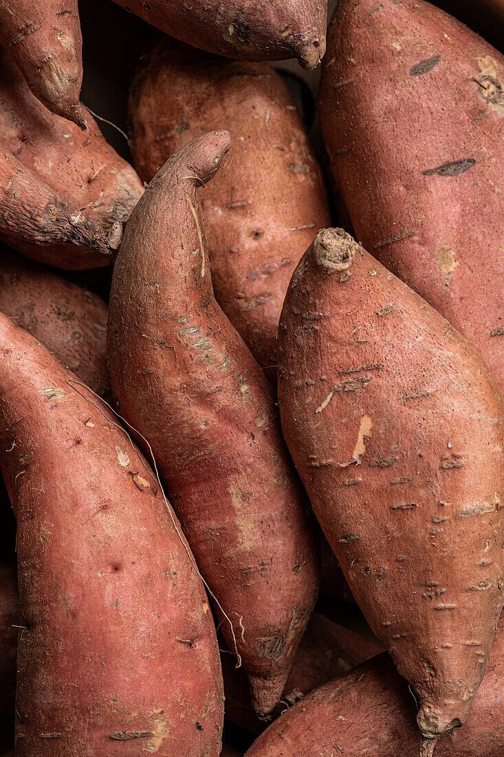 From above full frame of red raw sweet potatoes placed together as background