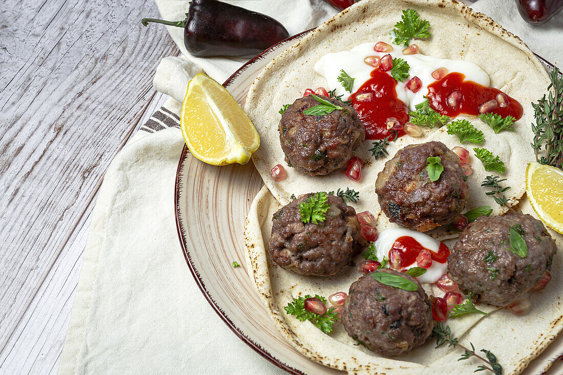 Traditionelle hausgemachte Rind- und Lammfleischbällchen mit arabischem Brot, Tomatensauce, Granatapfel und Kräutern. Halal-Essen