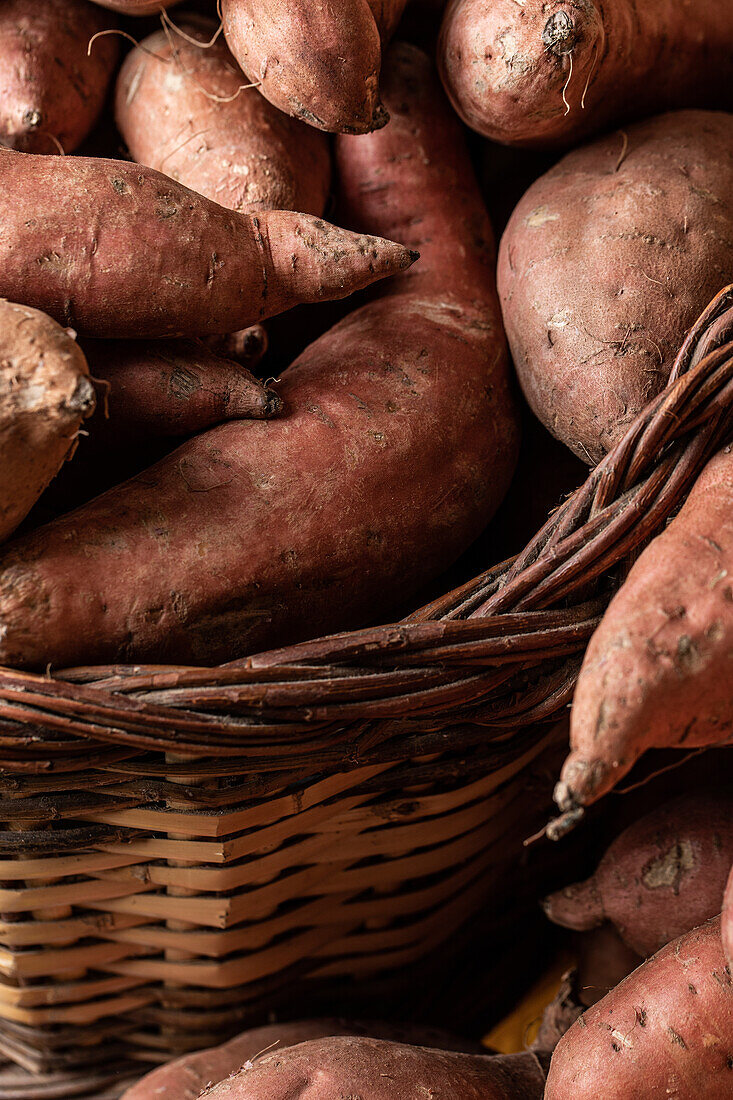 Red raw sweet potatoes placed together in a basket