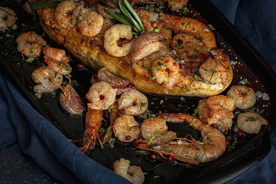 From above of black tray with appetizing baked swordfish served with prawns and confit garlic