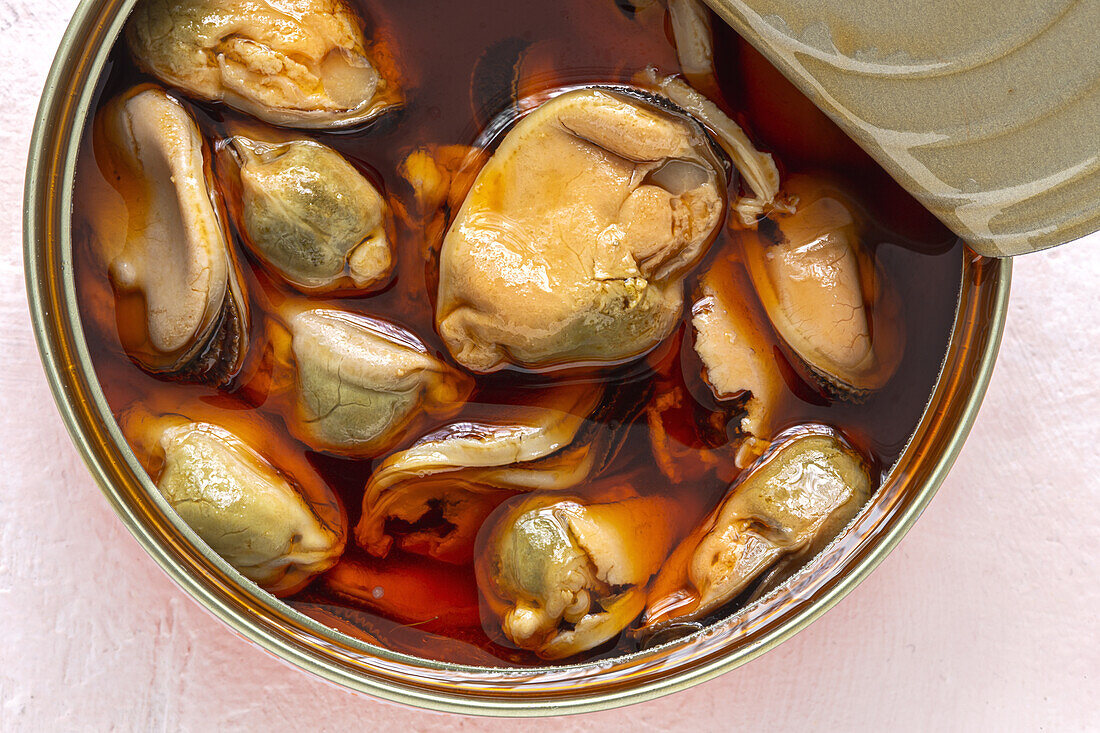 Top view of appetizing mussels in a open can with sauce on table
