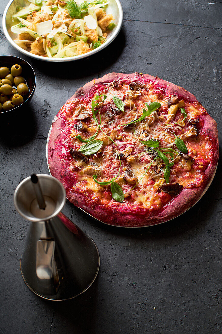 Purple colored rustic pizza with beetroot and vegetarian topping. Top view healthy food recipe