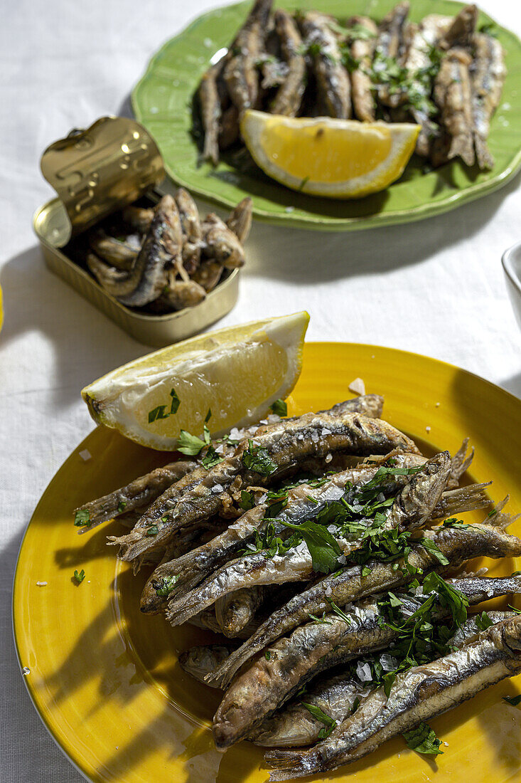 Von oben Teller mit appetitlichen gegrillten Sardellen, serviert auf einem Tisch mit einem Stück Zitrone und frischen Kräutern in einem Restaurant