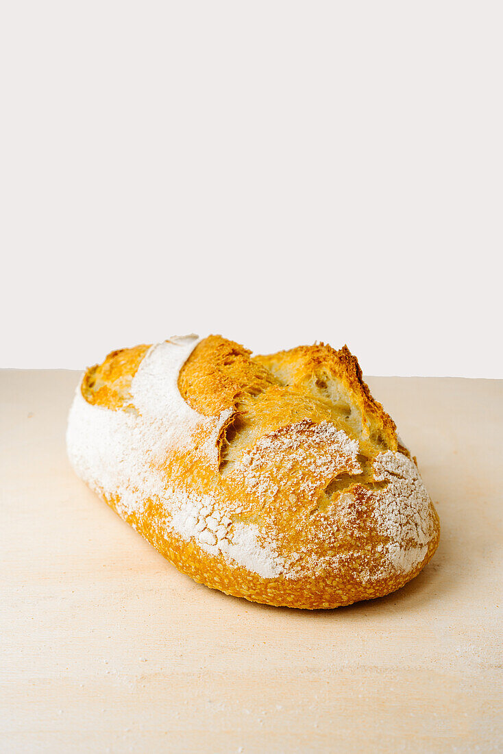 Leckeres Brot mit Mehl auf goldener Oberfläche in einer Bäckerei auf weißem Hintergrund