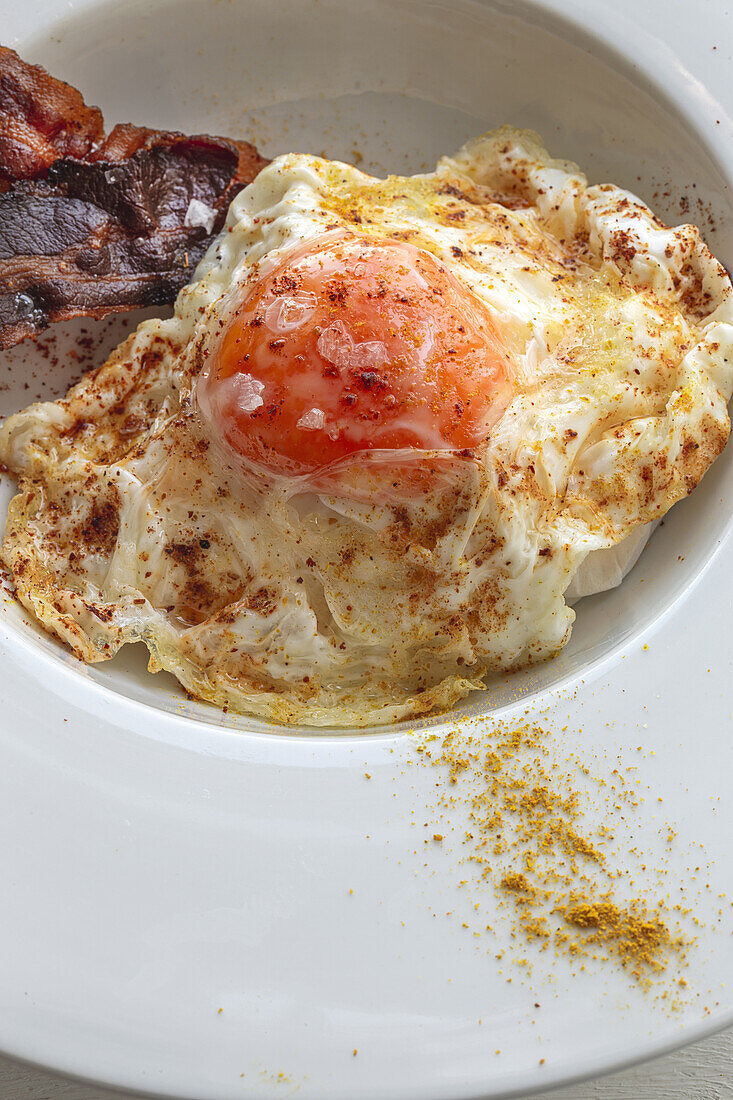 Overhead view of tasty eggs with fried bacon strips on plate