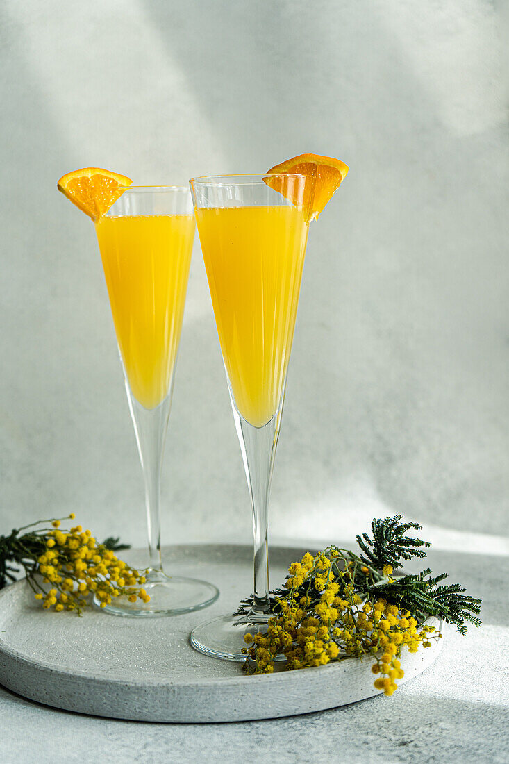 Glass of mimosa cocktail on stone background in sunny day