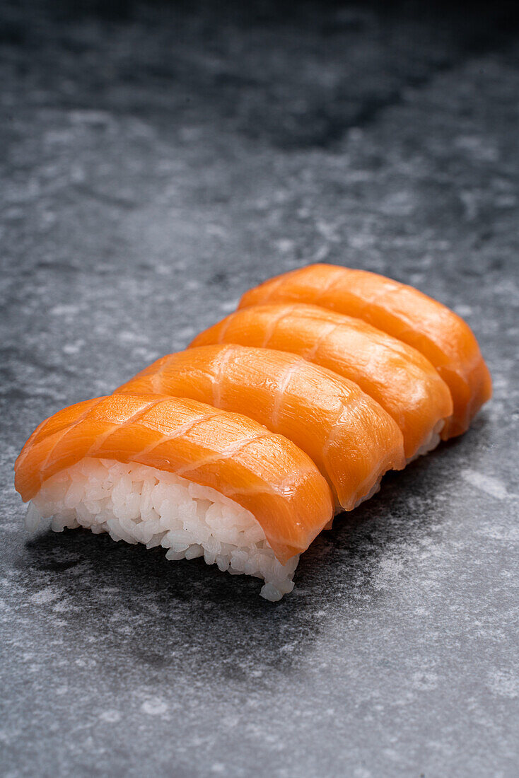Set von ähnlichen schmackhaften traditionellen japanischen Sushi mit weißem Reis und frischem Lachs auf Marmortisch in hellem Raum serviert