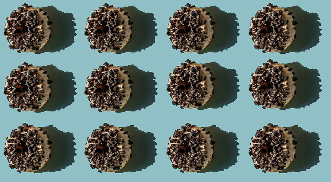 Top view of many white donuts covered with bits of oreo biscuit on blue background