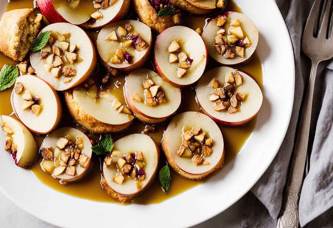 Top view of white plate with appetizing ripe apples served with nuts and mint leaves in syrup