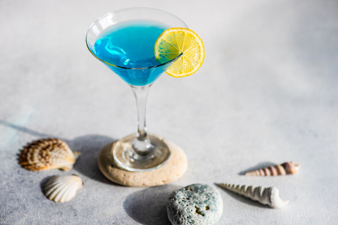 Glass of blue kamikaze drink on stone in modern style