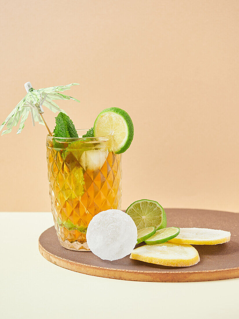 Glass of delicious nonalcoholic cocktail with lime and lemon slices decorated by mint leaves on wooden board