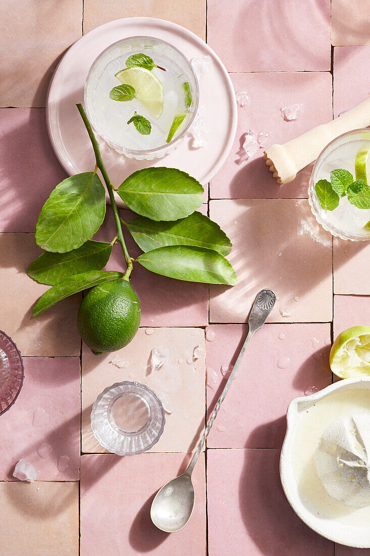 Top view of fresh mojito cocktail made with lime slices and mint placed on pink tile