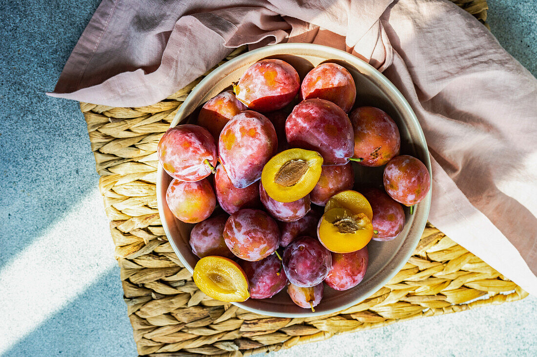 Fresh organic and ripe plum fruits in the bowl on concrete background