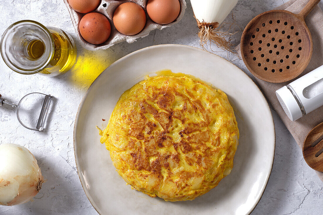 Appetitliches traditionelles spanisches Omelett auf dem Tisch mit Eiern und Zwiebeln in der heimischen Küche von oben