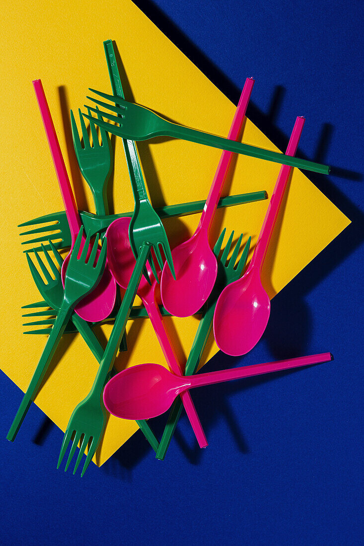 Overhead view of bright colorful eco friendly cutlery near yellow carton sheet