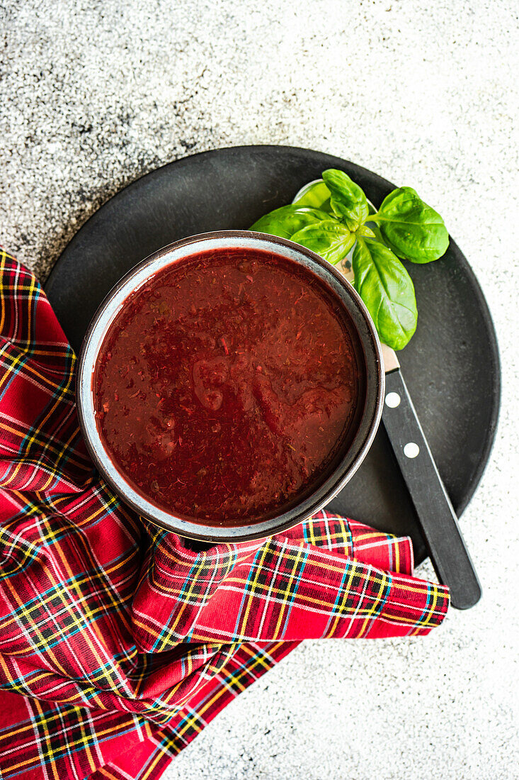 Rote-Bete-Cremesuppe, serviert in einer schwarzen Keramikschale mit frischem Basilikumkraut