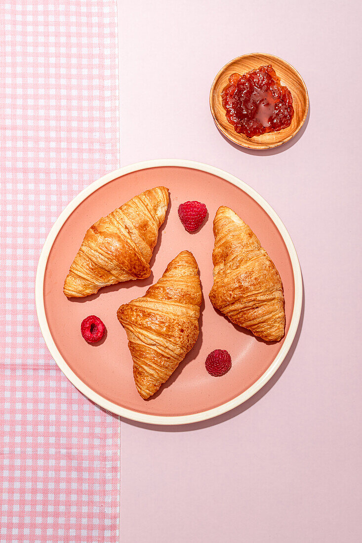 Von oben der Zusammensetzung der plated mit frisch gebackenen süßen Croissants serviert mit Beeren und Marmelade auf rosa Tisch platziert