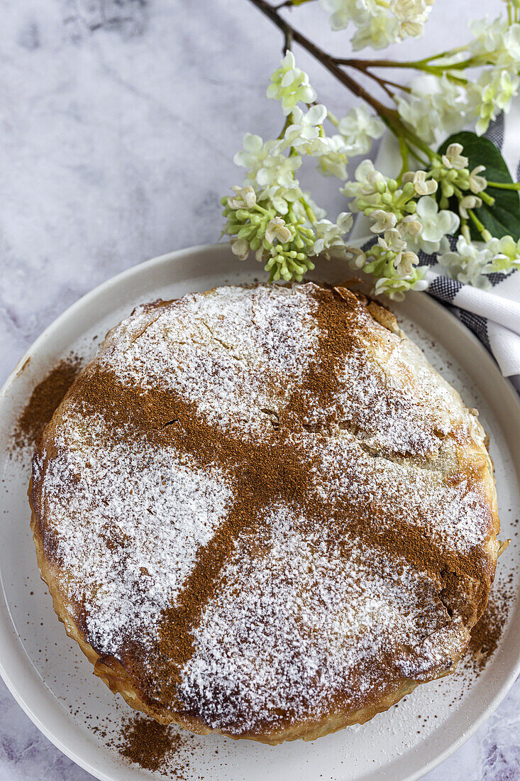 Top view of appetizing bastilla with aromatic spices on table near flower sprig during Ramadan holidays