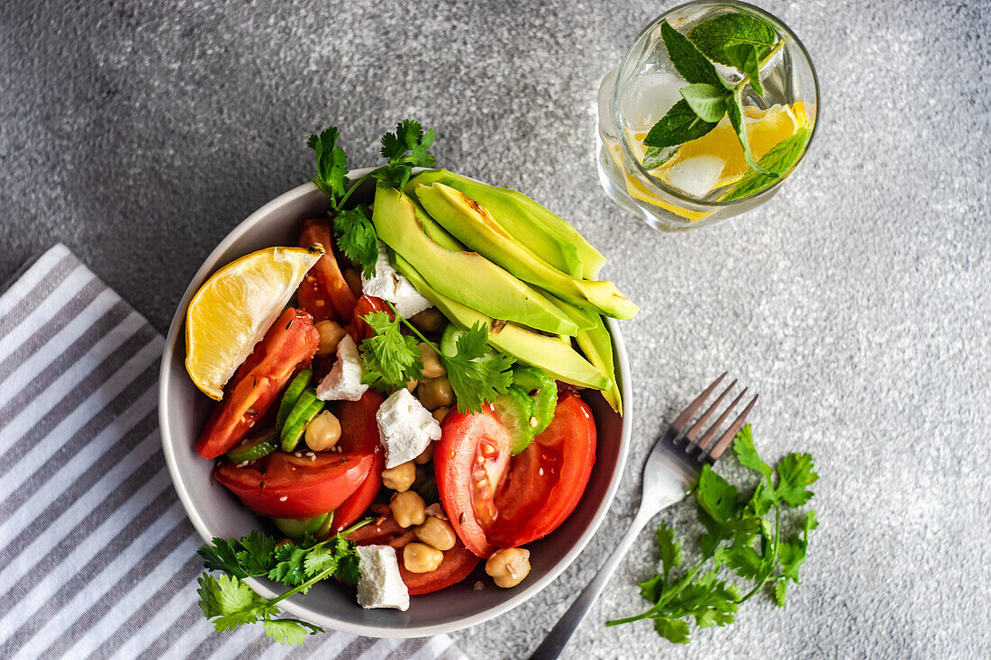 Von oben gesunder Salat mit biologischem Gemüse der Saison und Avocado auf einem Betontisch serviert