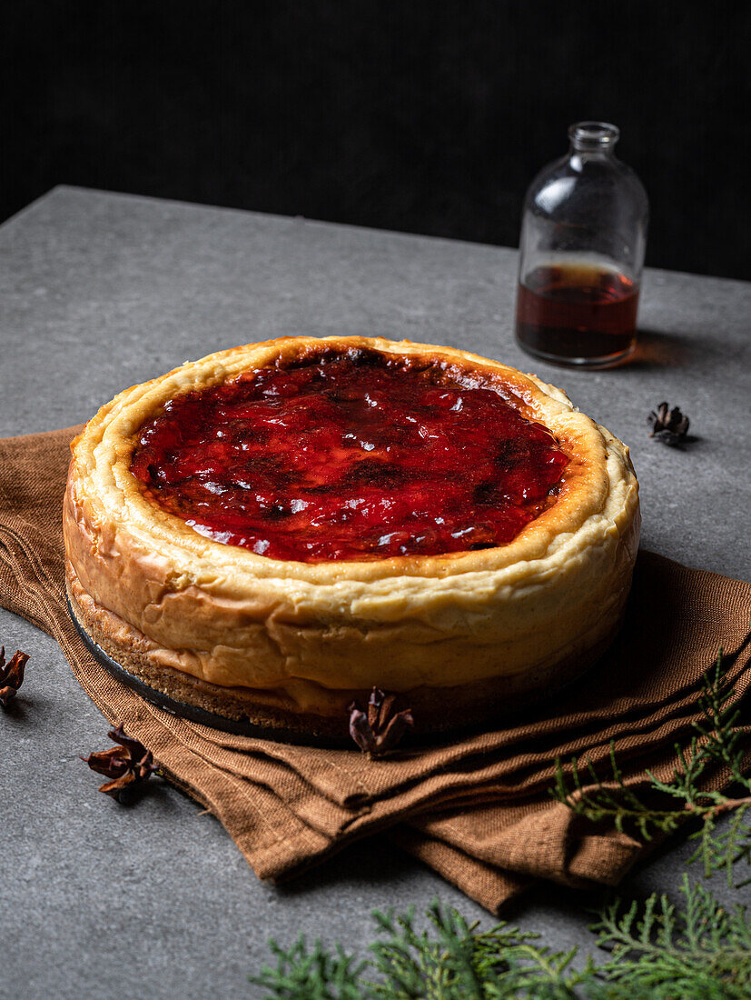 Yummy homemade sweet cheesecake placed against jar with jam on gray table