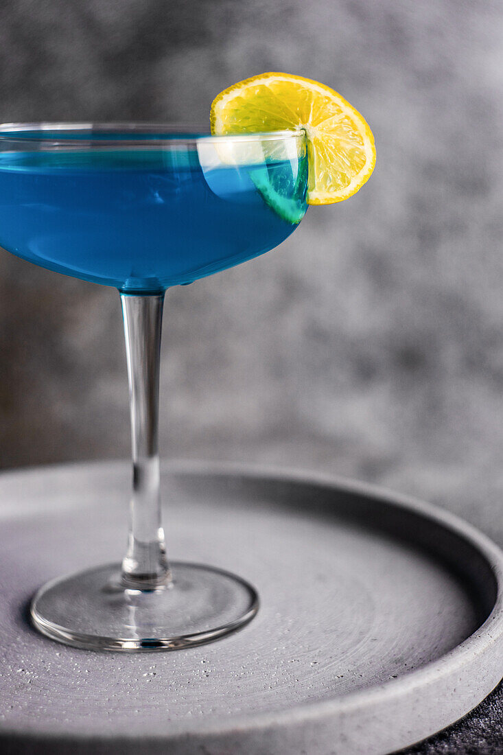 Glass of blue kamikaze drink on stone table in modern style