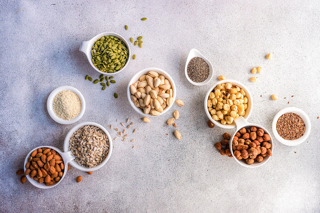 Top view of bowls full of nuts and seeds on concrete background