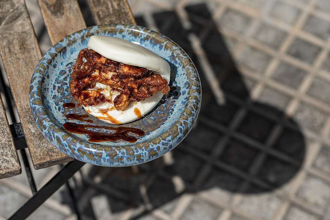 From above of delicious Japanese pan bao bun with fried soft shell crab served on corner of table on terrace of restaurant