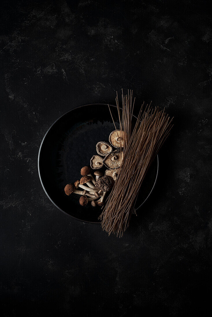 Frische Pilze und harte braune Nudeln in der Pfanne zum Kochen des koreanischen Gerichts Japchae