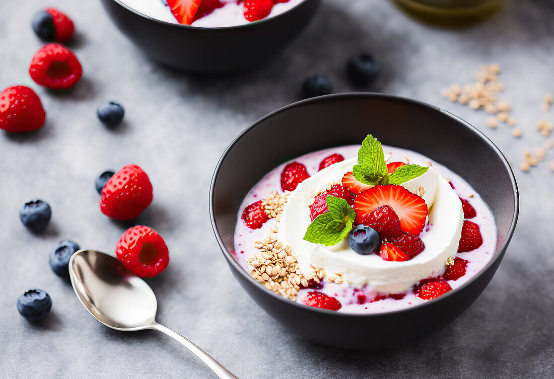 Appetizing sweet dessert with fresh strawberries and blueberries served on yogurt with muesli in bowl