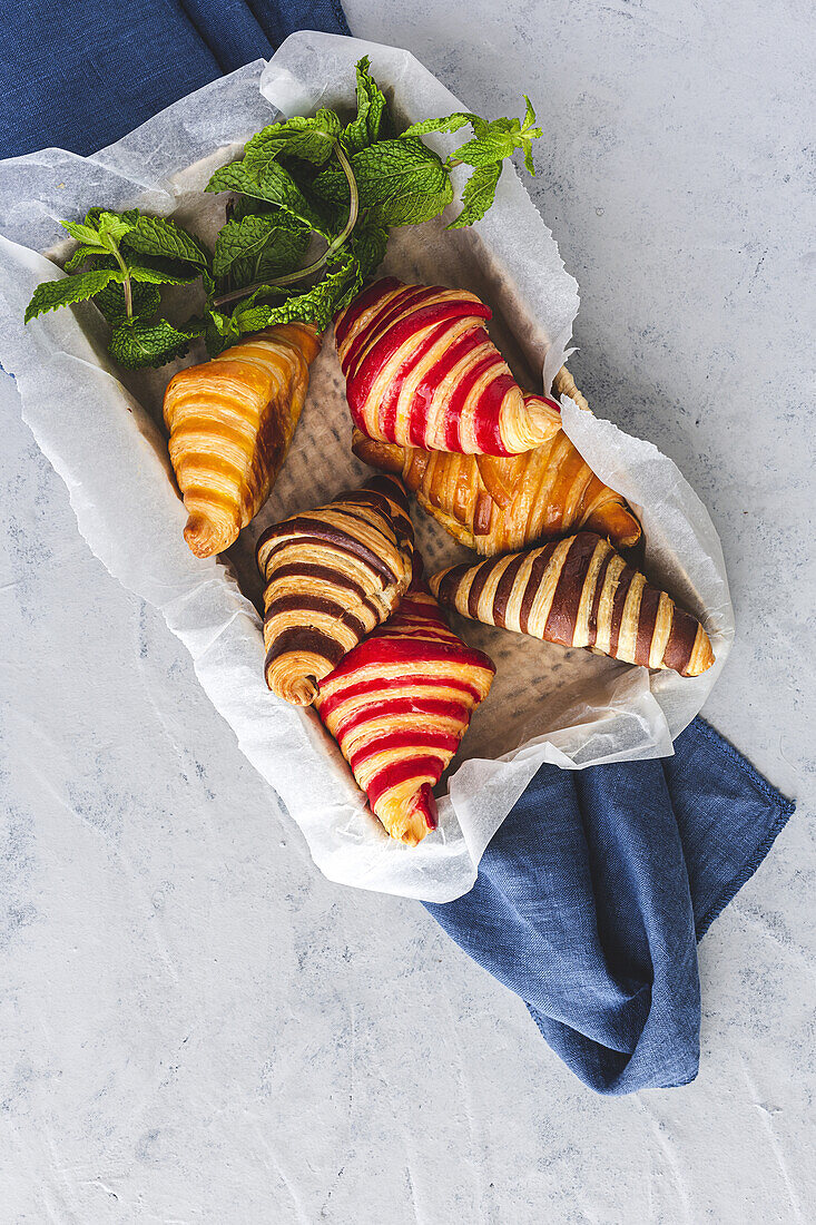 Blick von oben auf verschiedene süße Croissants, die in einem Korb auf dem Frühstückstisch serviert werden