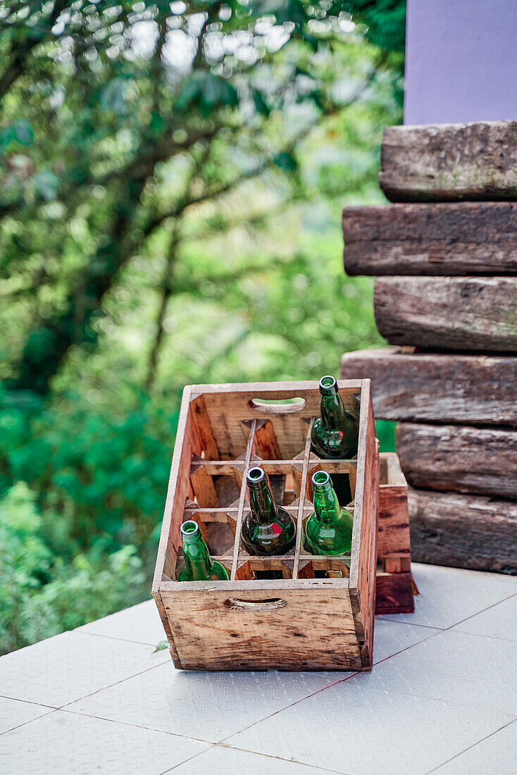 Wooden box with various beer bottled placed on table in green garden on sunny summer day