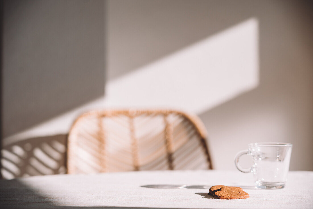 Glass on table with heart shaped cookies on sunny day in kitchen