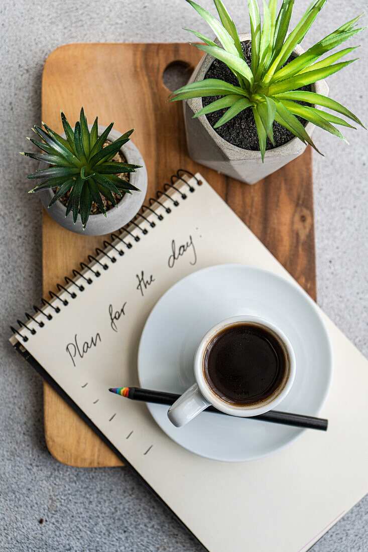 Plans for the day and morning cup of coffee on the table with green plants in the pot