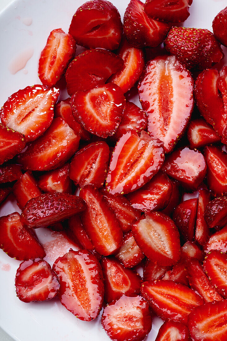 In Scheiben geschnittene Erdbeeren mit Zucker überzogen auf einem Teller. Kochen von Dessert oder Marmelade