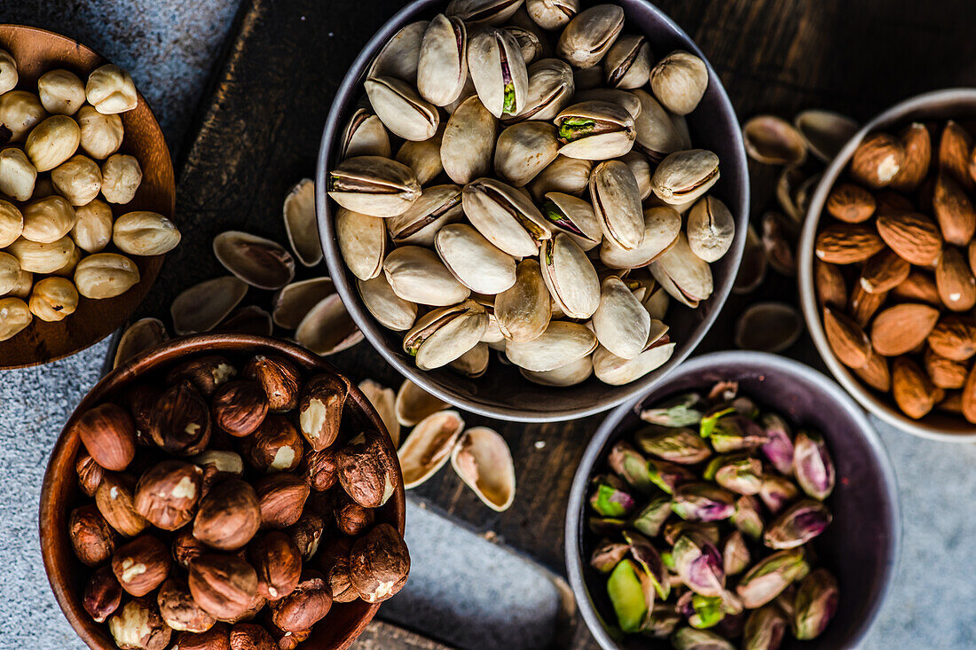 From above bowls with different kinds of nuts on concrete table background