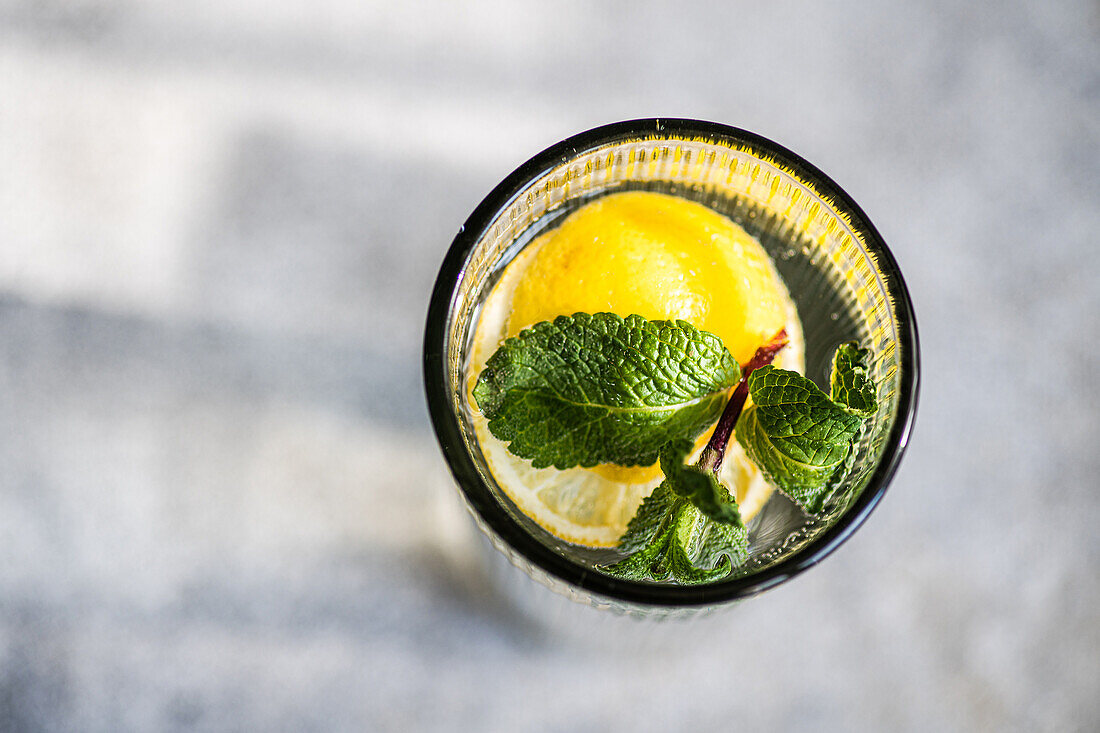 Mojito-Cocktail mit Minze und Zitrone, serviert in einem Kristallglas auf einem Betontisch