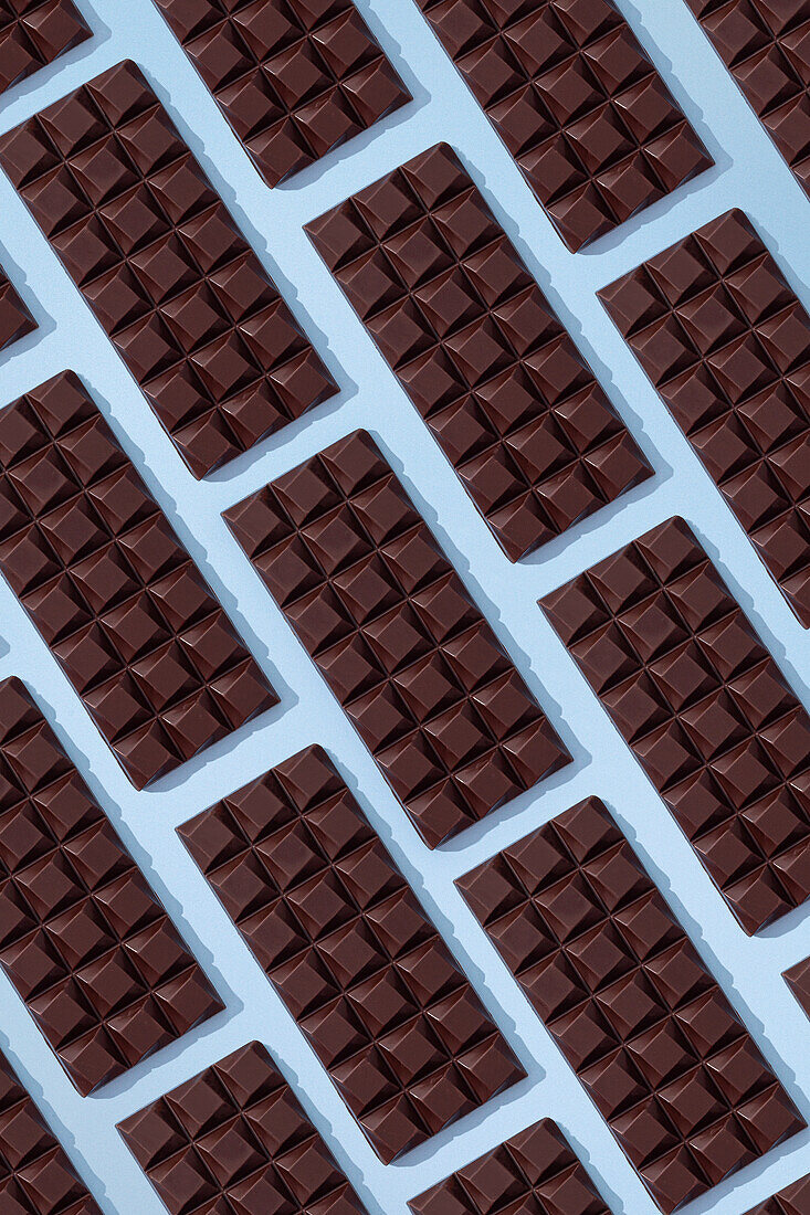 Top view minimalistic composition with pieces of handmade pink chocolate bar on blue background