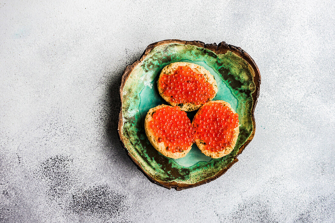 From above bruschetta with red caviar on ceramic plate on stone table