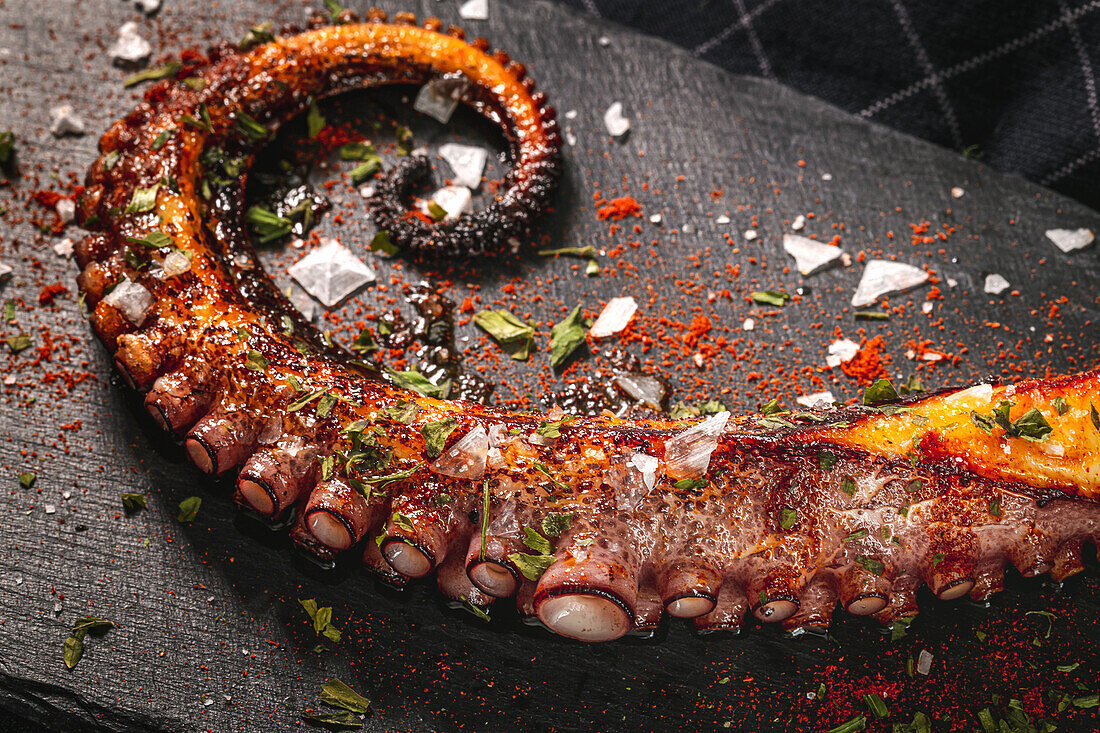 Delicious grilled octopus tentacle served with spices on wooden board