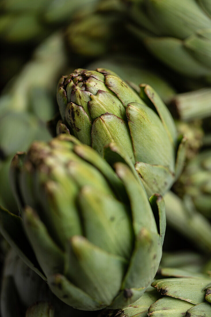 Full frame of bunch of fresh green artichokes placed on stall in local market