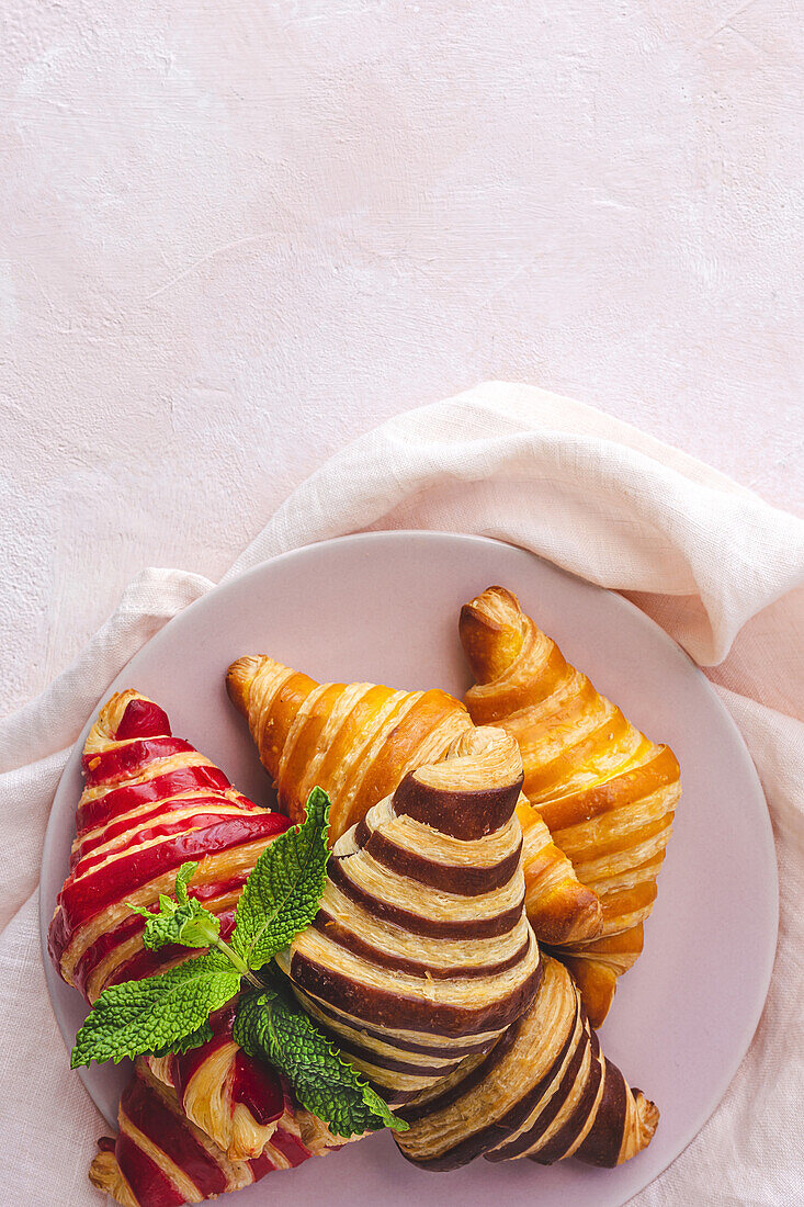 Blick von oben auf verschiedene süße Croissants, die in einem Korb auf dem Frühstückstisch serviert werden