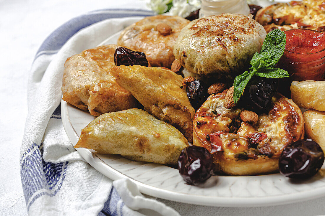 Blick von oben auf verschiedene leckere arabische Speisen mit Salsa und frischen Minzblättern in der Nähe von Mandeln während des Ramadan-Festes