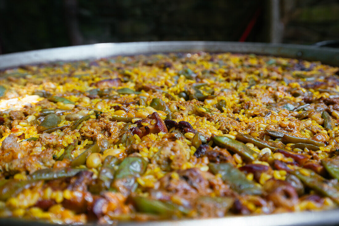 Nahaufnahme einer köstlichen traditionellen spanischen Paella mit Huhn und Bohnen im Garten