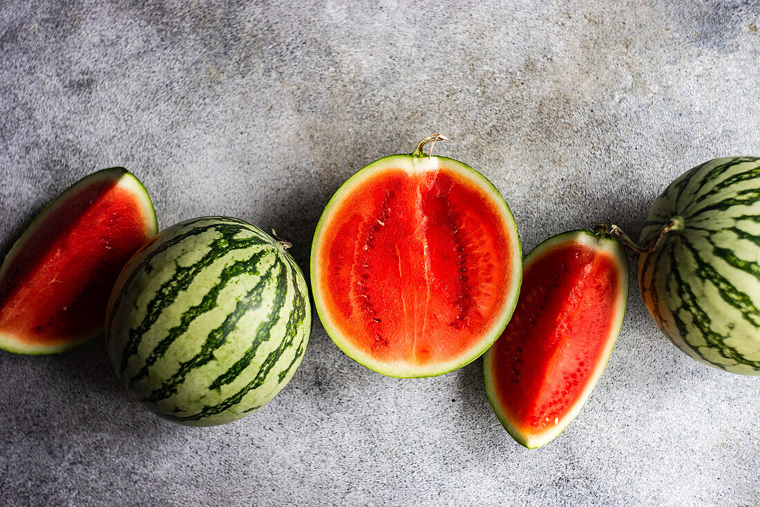 From above still life composition of sliced ripe striped green watermelon on concrete background