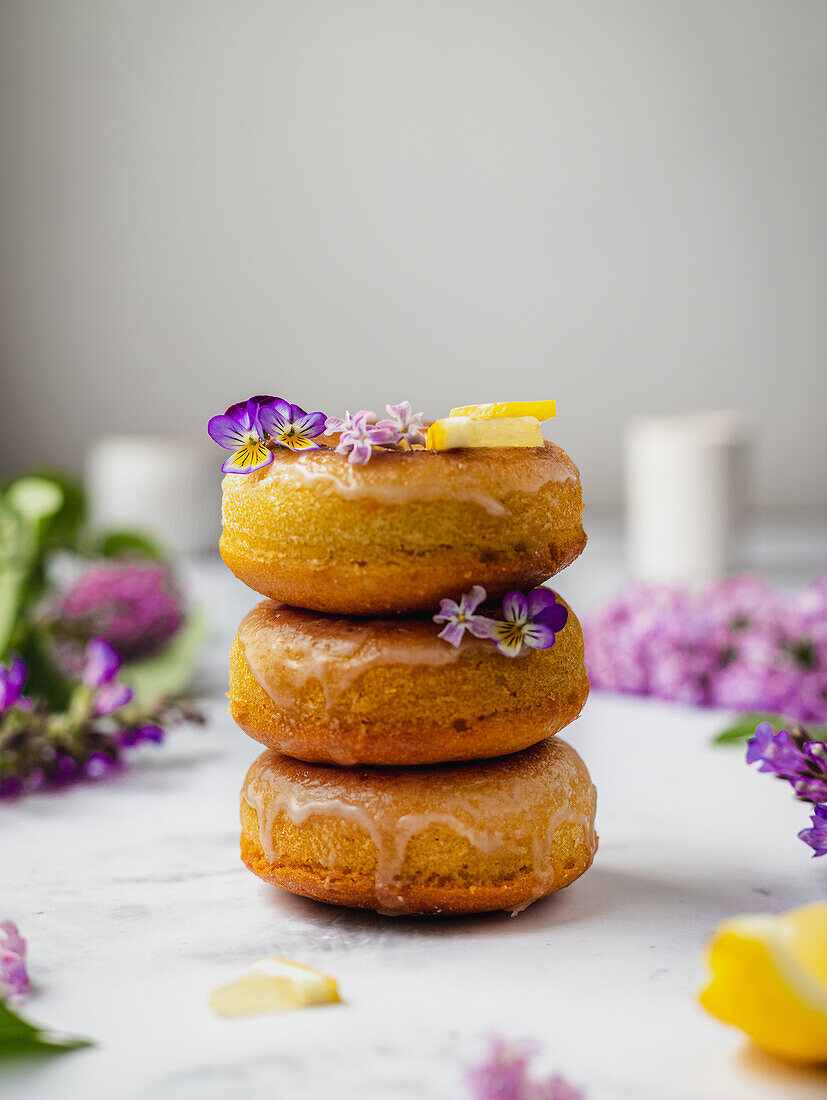 Ein Stapel leckerer Donuts mit frischen Zitronenstücken und blühenden Lavandula-Blüten auf süßer Glasur