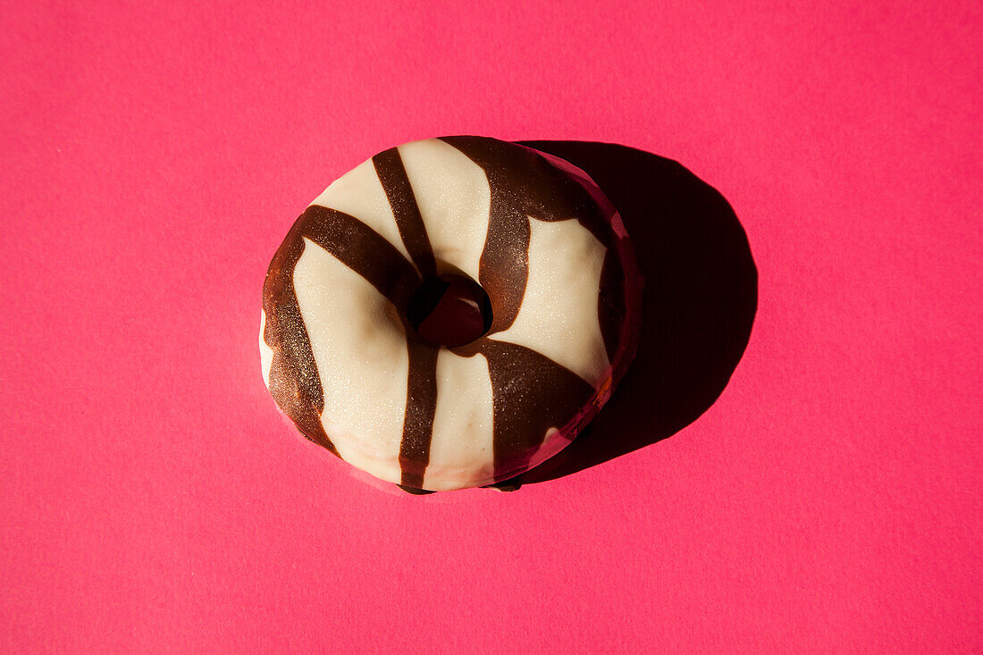 White donuts coated oreo chocolate cookie pieces on pink background